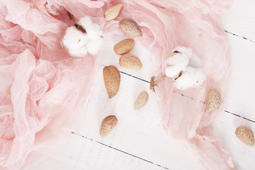 almonds and cotton with rose textile on whte wooden table
