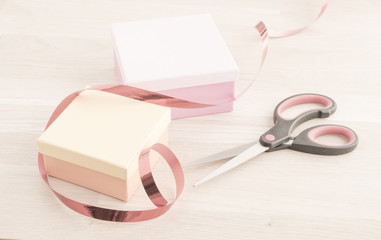 Gift wrapping for a holiday celebration, birthday or surprise party. Preparation of present with ribbon, box and decoration on table. Festive package material.