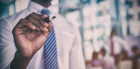 Midsection of businessman writing with marker on glass