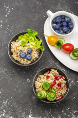Healthy breakfast snack. Quinoa bowl with fresh vegetables, berries and herbs on a marble background in portioned bowls    . Top view