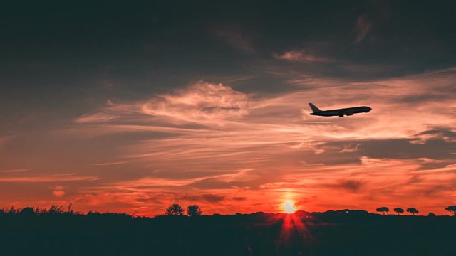 Side Silhouette of a Passenger airplane is departing against a beautiful sunset.