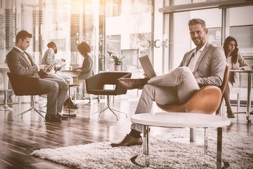 Obraz premium Smiling businessman using laptop in office