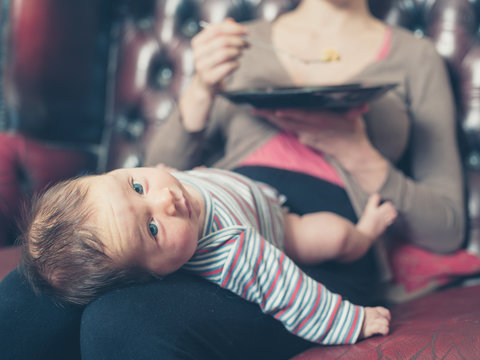 Young mother having dinner with baby on lap