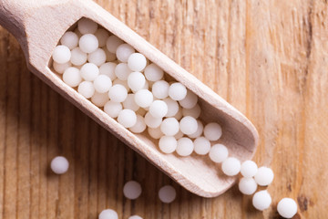 Closeup image of homeopathic medicine consisting of the pills and a bottle containing a liquid homeopathic substance.
