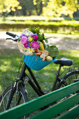 Fototapeta na wymiar Bicycle basket filled with fresh vegetables and flowers.