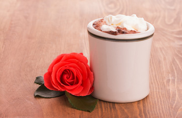 Romantic red rose with a cup of hot chocolate on wooden table - concept of a sweet gesture