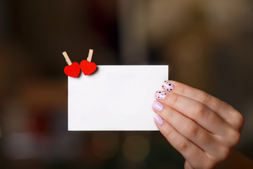 Woman hand holds paper card with two heart pins. Valentines day concept. Copyspace for text.