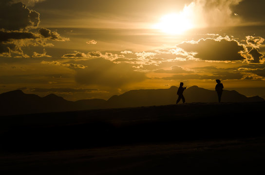 Silhouettes of two people walking on White Sand Dunes during sun