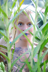 Tattooed woman peeking through tall grass