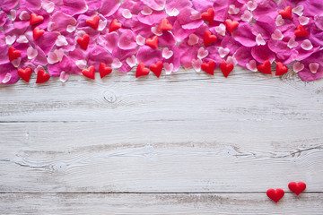 Wooden background with rose petals and hearts