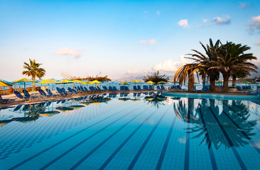 Nice view on the swimming pool with palm trees on the shore of the Mediterranean Sea in Greece. Crete