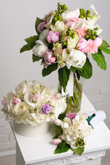 Bouquet of white peonies. flower composition on white table. Bouquet paper box. vase in the background.