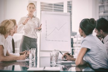 Businesswoman giving explication in front of a growing chart