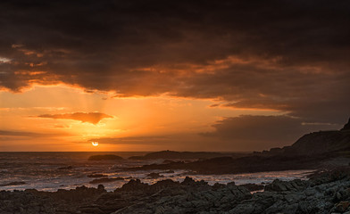 Cloudy sunset at rocky shore
