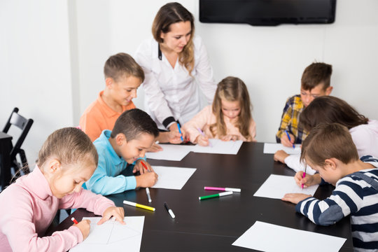 glad little children with teacher drawing in classroom