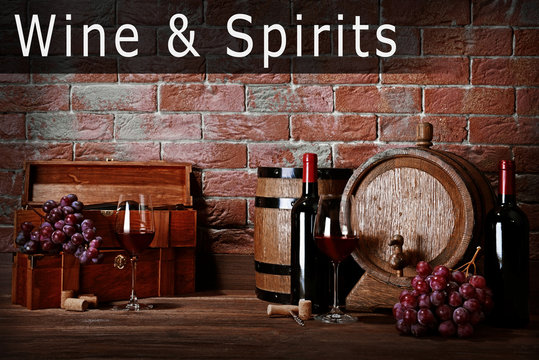 Composition with wine and grape on wooden table. Text WINE AND SPIRITS on brick wall background