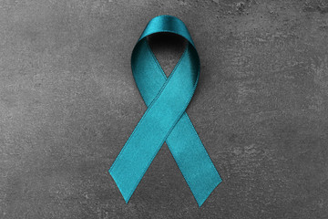 Sea-green ribbon on dark background. Ovarian cancer and gynecological disorders concept