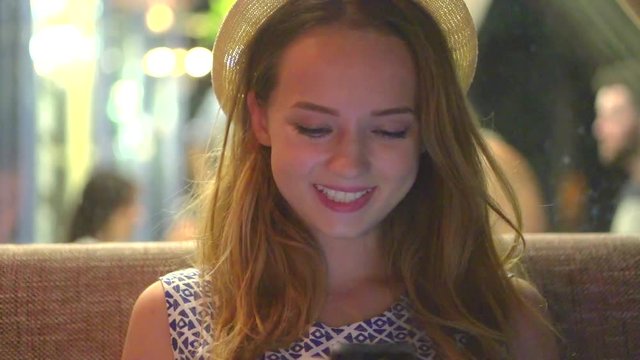 Beauty Girl sitting in sushi bar and using her smartphone at night. Teenage hipster girl chatting with her friends in restaurant, smart phone, technology concept. Full HD 1080p