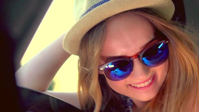 Happy young woman sitting in car passenger seat and looking out window on sunny day. Hipster teenage girl enjoying rural car ride. Trip. Vacation. Full HD video footage 1080p. Slow motion 240 fps