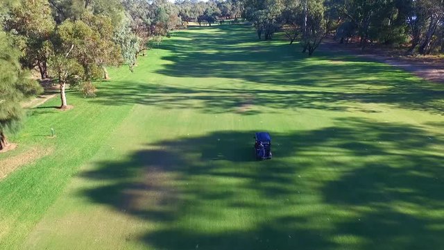 Drone aerial view of Golfers in Electric Golf Buggy with Caddy driving through Golf Course.
