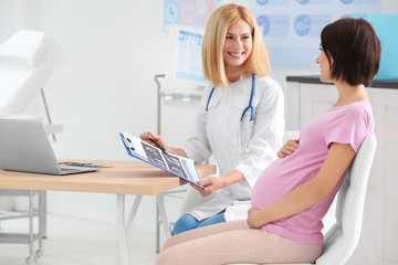 Doctor showing ultrasound photo to pregnant woman