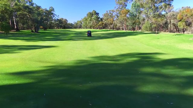Drone aerial view of Golfers in Electric Golf Buggy with Caddy driving through Golf Course.
