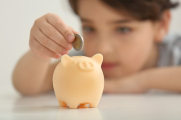 Obraz na płótnie Canvas Piggy bank and little boy with coin on background, close up