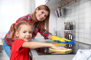 Little girl and her mother doing cleanup in kitchen