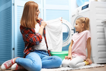 Pretty woman and her daughter doing laundry at home