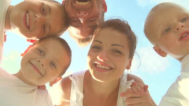 Happy laughing big family having fun outdoors. Father, mother and three children standing together in a circle over sky. Slow motion 240 fps, Full HD