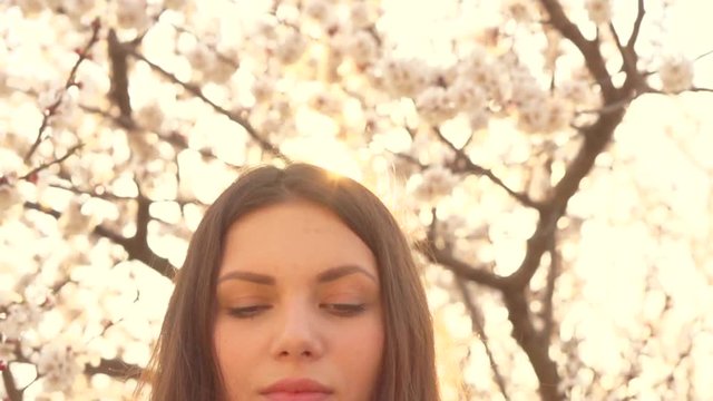 Beauty girl outdoor enjoying nature in blooming orchard. Spring blossoming trees. Slow motion. High speed camera. Full HD 1080p