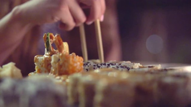 Young woman eating sushi rolls in japan restaurant, sushi bar. Beauty girl eats Japanese food. Slow motion 240 fps, high speed camera shot. Full HD 1080p