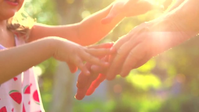 Grandma and child hands. Granny's Old hands playing with Child together. Happiness. Hands of baby and grandmother close up in sun light. Slow motion 240 fps. Full HD 1080p