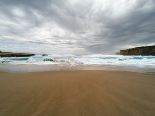Waves rolling in on a beach at the Twelve Apostles Marine National Park, Australia