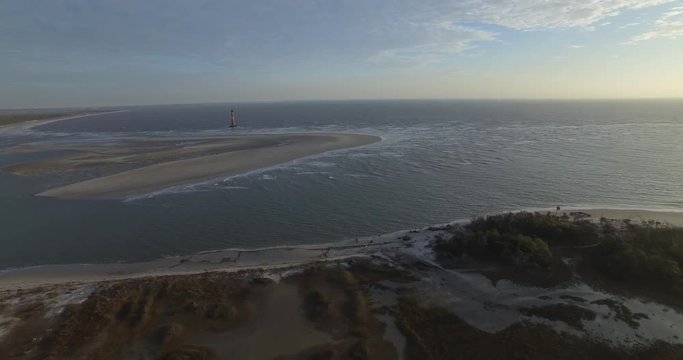 Aerial shot of a coastal marsh and forest with a Lighthouse on Folly Beach in South Carolina.