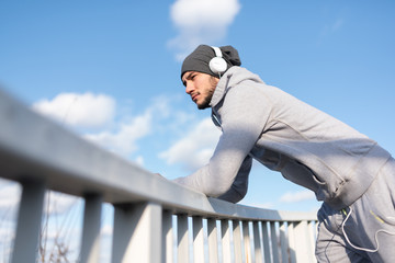 A young athlete man with headphones resting listening music thinking