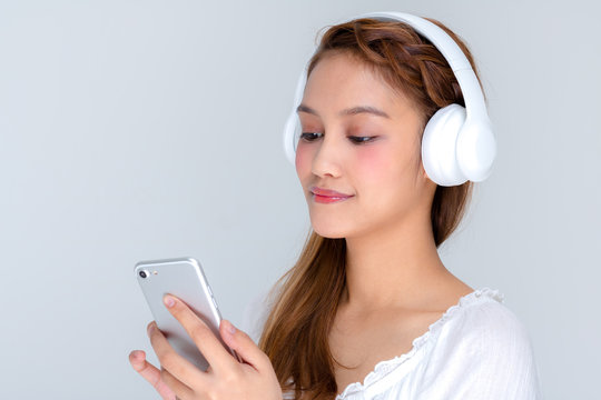 young woman listening music with smart phone and wireless headphone, half latina and half asian