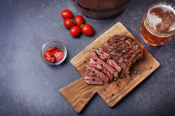 Tasty grilled steak with beer on cutting board