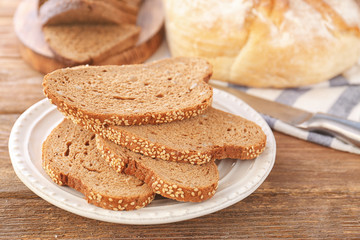 Fototapeta na wymiar Plate of sliced bread on wooden table closeup
