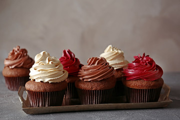 Metal tray with tasty chocolate cupcakes on dark textured table
