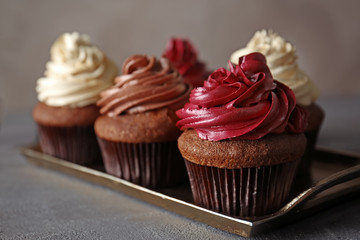 Metal tray with tasty chocolate cupcakes on dark textured table, close up