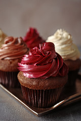 Metal tray with tasty chocolate cupcakes on dark textured table, close up