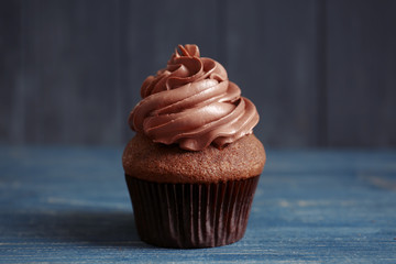 Tasty chocolate cupcake on wooden table
