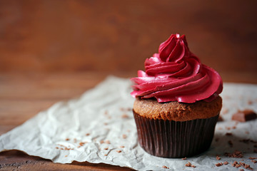 Tasty chocolate cupcake and paper napkin on wooden table