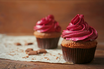 Tasty chocolate cupcake and paper napkin on wooden table