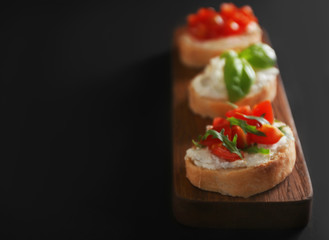 Tasty bruschettas on dark background, closeup