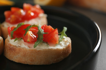 Tasty bruschetta on black plate