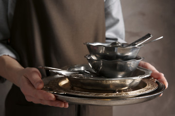 Closeup of woman holding tray with silver dishware