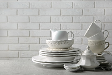 Porcelain dishware on table and white brick wall background