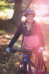 Fototapeta premium Portrait of female biker with mountain bike in countryside